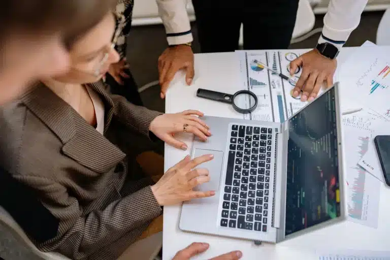 Deux personnes analysent des données marketing sur un ordinateur portable au bureau.