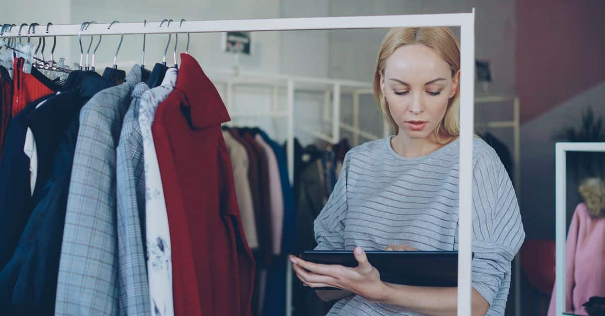 Commerçante consultant son téléphone dans sa boutique de vêtements