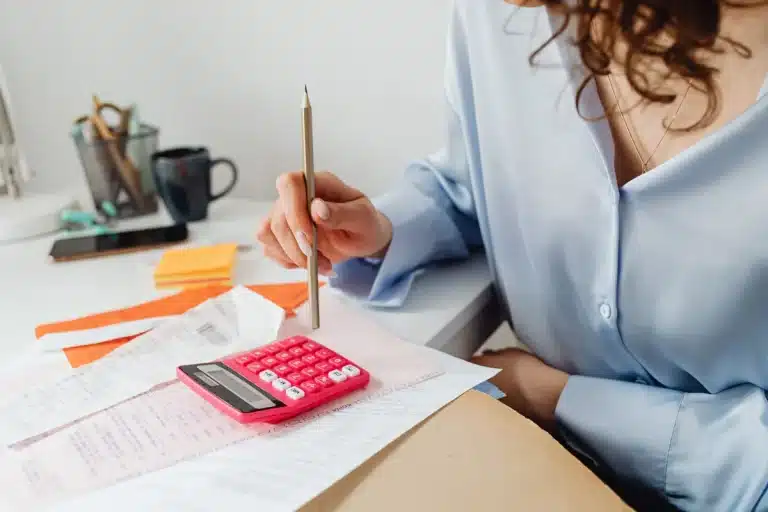 Facture papier, calculatrice et stylo sur un bureau.