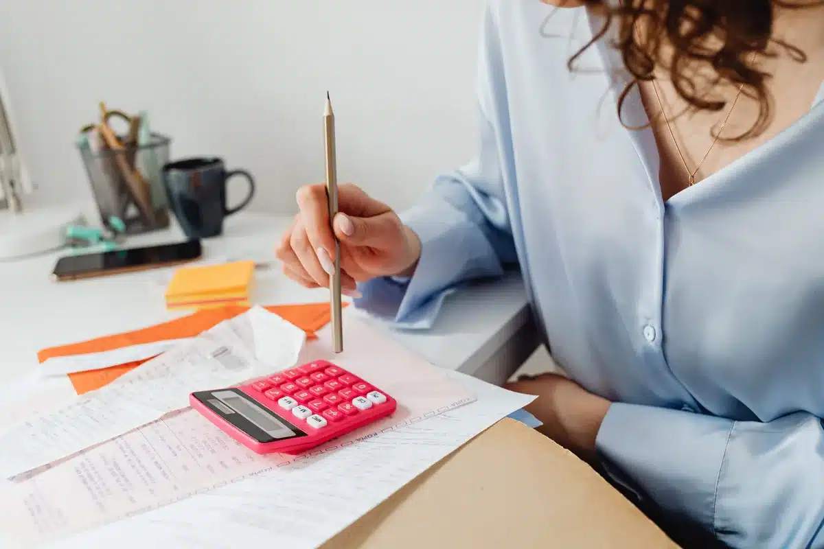 Facture papier, calculatrice et stylo sur un bureau.